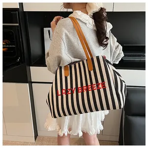 Détail du sac cabas en toile avec rayures verticales noires et blanches et broderie rouge