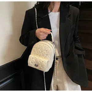 Detail showing creamy white quilted mini backpack with rhinestone embellishments and chain