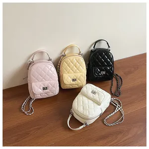 Détail de quatre mini sacs à dos matelassés en rose, jaune, noir et blanc avec chaîne