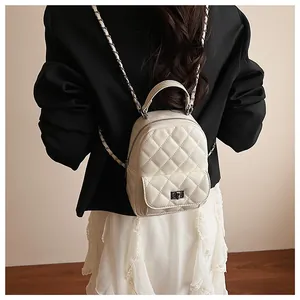 Détail d'un mini sac à dos matelassé crème avec bandoulière chaîne porté par un mannequin