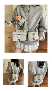 Detail of white quilted crossbody bag with silver rose pendant and elegant chain handle