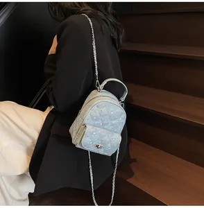 Detailed view of quilted denim mini backpack with sparkling rhinestones and chain straps