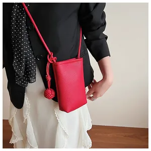 Detailed texture of red litchi leather mini crossbody bag with knot charm on model
