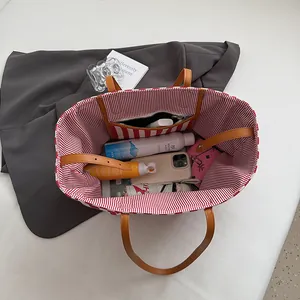 Vue de dessus du sac cabas en toile avec doublure à rayures rouges et anses en cuir