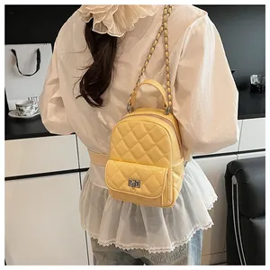 Détail du mini sac à dos matelassé jaune avec chaîne en argent et fermoir rotatif