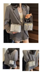 Close-up of silver matelassé quilted box bag with floral zipper and metal chain strap