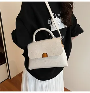 Détail du sac mallette en cuir grainé blanc avec fermoir doré et poignée supérieure