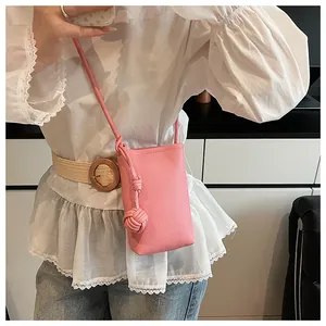 Detail of pink mini crossbody bag featuring lychee texture and knot strap decoration