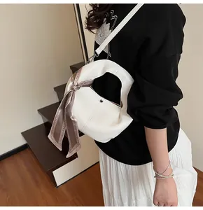 Detail of off-white lychee leather crescent bag with patterned silk scarf decoration