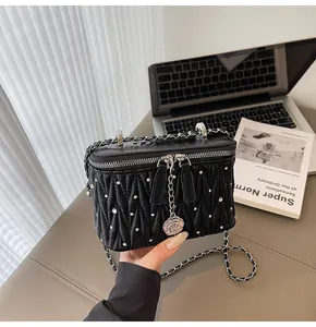 Detail of black quilted vanity bag featuring silver studs and camellia flower zipper charm