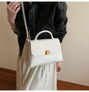 Détail de la texture cuir litchi blanc et du fermoir doré sur le sac à bandoulière chic