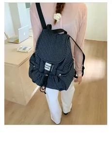 Detail of blue grid drawstring backpack featuring multiple pockets and white label