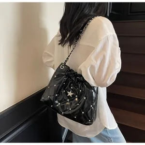 Detail of black quilted shoulder bag with sparkling star rhinestones and chain strap