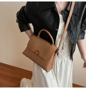 Gros plan du sac à main en cuir camel à texture litchi et boucle dorée sur un mannequin