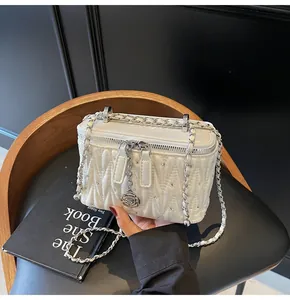 Detail of white quilted box bag with silver rhinestones and a rose charm pendant