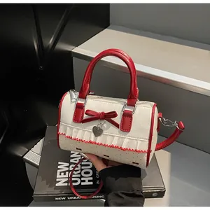 Détail de la dentelle blanche, du nœud rouge et du pendentif cœur sur le sac cylindrique