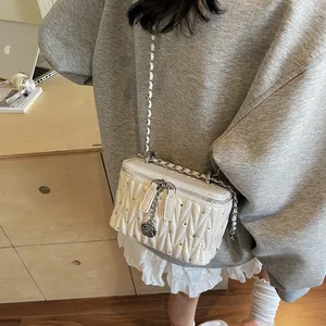 Chic quilted pearl white crossbody bag with silver studs and leather chain strap on a model