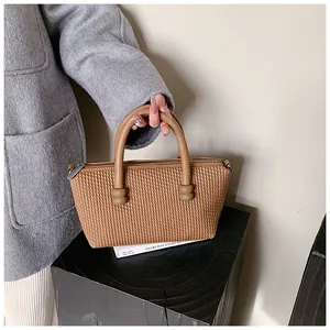 Détail de la texture tissée caramel et des poignées en cuir du sac à main chic