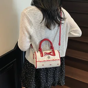 Sac cylindre blanc élégant avec imprimés nœuds rouges et détails de dentelle