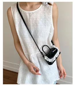 Dettaglio della mini borsa nera con bordo in pizzo bianco e finitura lucida