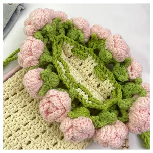 Primer plano de mini bolso de ganchillo hecho a mano con rosas rosas 3D y hojas verdes