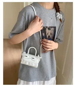 Primo piano di una mini borsa bianca con fiocco e pizzo delicato su una modella