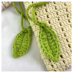Detalle de cerca de la bolsa de ganchillo crema con adornos decorativos de hojas verdes