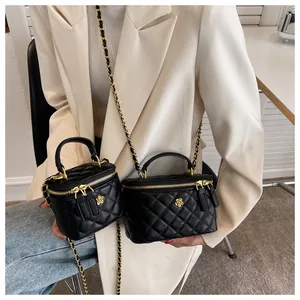 Primer plano de mini bolsos tipo caja en cuero acolchado negro con cadenas doradas y logo