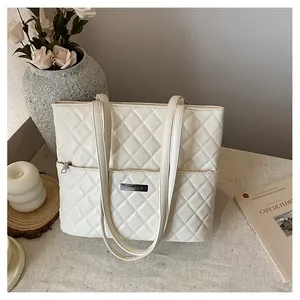 Detail shot of a beige quilted tote bag with silver logo on a decorative table