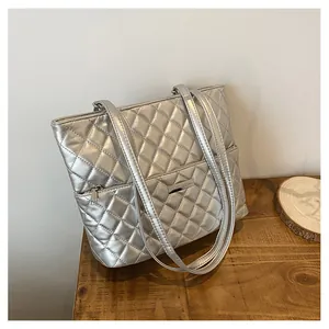Detail of silver quilted tote bag showing high-quality stitching and metal brand logo