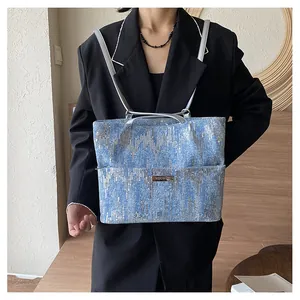 Detail of light blue tote bag with silver sequins and metallic brand logo plate