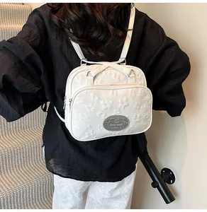 Détail du sac bandoulière blanc avec texture jacquard florale et plaque logo en métal