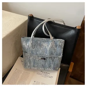 Close-up of light blue denim tote bag with silver sequin wave pattern and metal logo