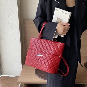 Chic red quilted tote bag with silver logo plate and top handles for stylish commuting