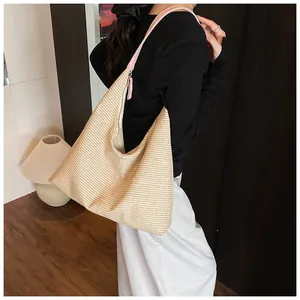 Detail of straw woven hobo bucket bag with pink leather strap and zipper closure