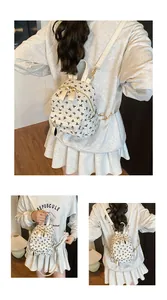 Detail view of cream mini backpack featuring black ribbon prints and gold-tone hardware
