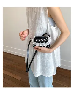 Detail of polka dot mini shoulder bag featuring elegant white lace trim and slim leather strap