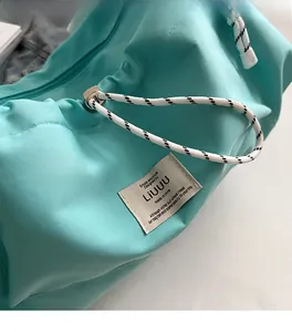 Dettaglio ravvicinato della borsa in nylon verde menta con cuciture e etichetta del marchio