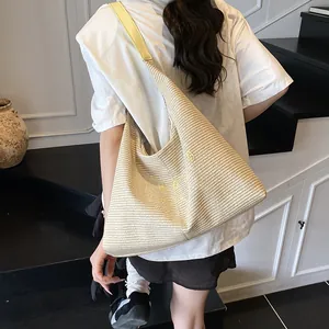 Large beige woven shoulder bag with yellow leather straps and graphic lettering