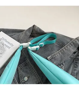 Dettaglio della tracolla regolabile in nylon con fibbia in plastica bianca su borsa azzurra