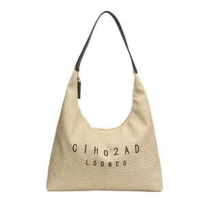 Large straw bucket bag with dark brown straps and artistic lettering for summer beach vacation