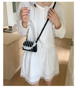 Polka dot mini crossbody bag with white lace trim detail shown on a female model