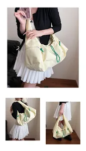 Dettaglio borsa hobo beige con coulisse verde, tasca zip e grande capienza