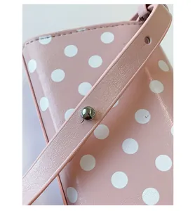 Detail of pink polka dot bag featuring silver metal stud and adjustable leather strap