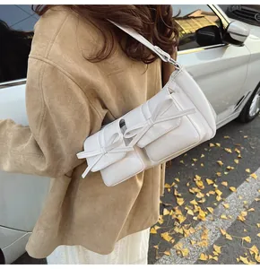 Detail der cremeweißen Lackleder-Schultertasche mit Taschen und süßen Schleifen
