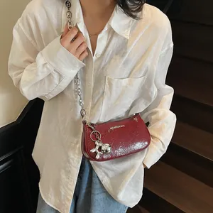 Deep red patent leather shoulder bag with chunky silver chain and balloon dog charm