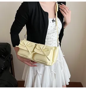 Gelbe Umhängetasche mit zwei Vordertaschen und eleganten Schleifendekorationen im Detail