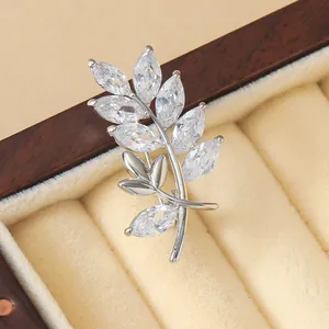 Broche élégante en forme de feuille avec zircons sur un coffret à bijoux en velours