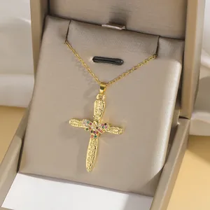 Golden cross necklace with colorful zircons and engraved details in a velvet jewelry box