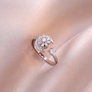 Dettaglio dell'anello fiore girevole in zircone con luna su tessuto in raso rosa